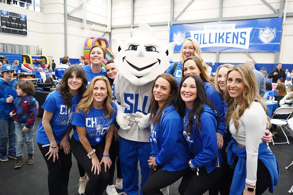 A group of women wearing SLU shirts pose for a photo with the Billiken.