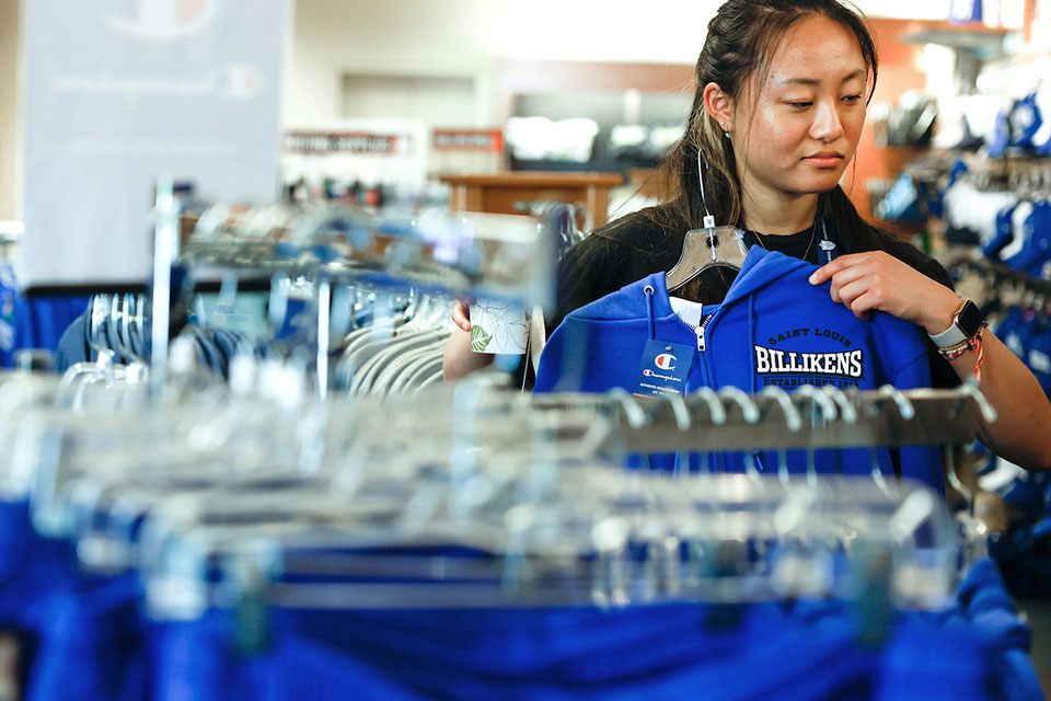 A student looks at a zip-up hoodie in the bookstore.