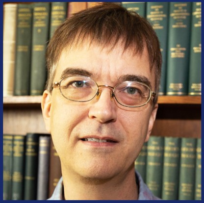 Keynote Speaker headshot standing in front of a book case