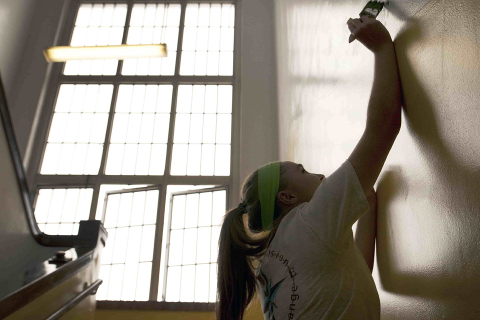 Student paints a wall as part of a service project