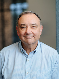 Curator René Paul Barilleaux, wearing a light blue dress shirt, gazes at the camera René Paul Barilleaux