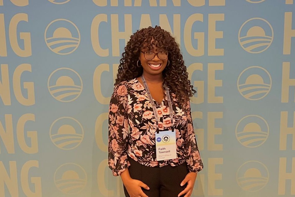 A woman smiles for a photo in front of a background that reads "Change."