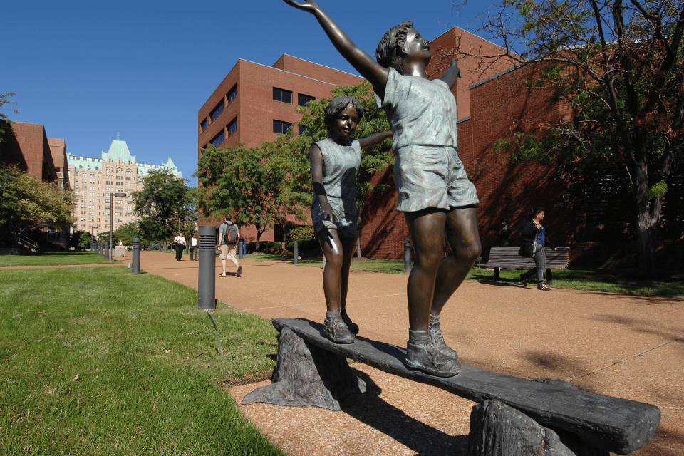 Statues of children on a bench in front of the Valentine School of Nursing.