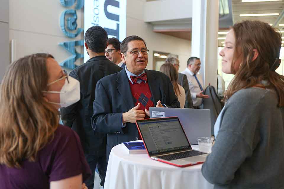 A man speaks to a group of people at an academic event.