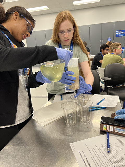 Two students observe a water filtration activity.